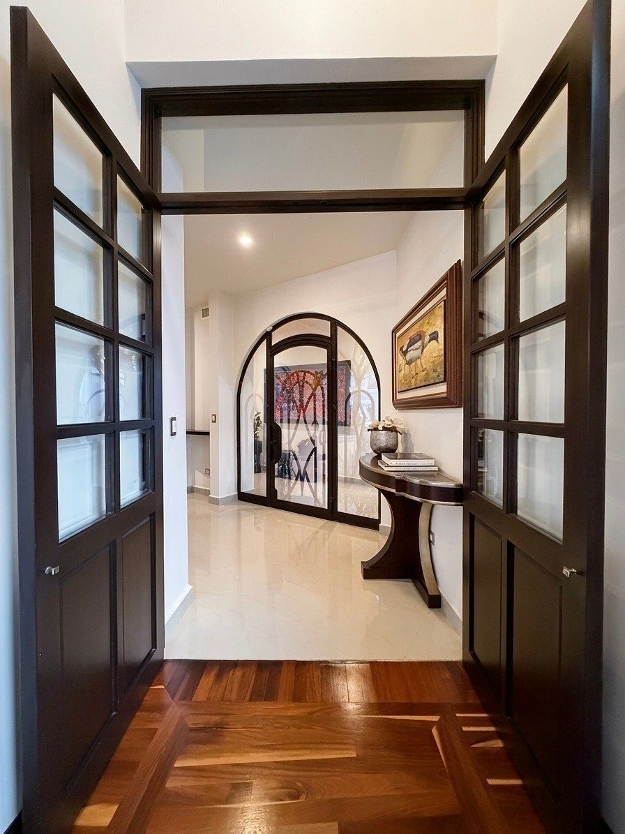 Recibidor con arco y puertas de cristal en Casa Colorines, San Pedro Garza García