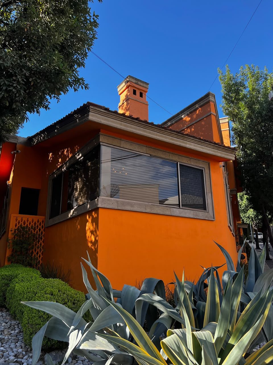 Fachada naranja de Casa Colorines en esquina, con agaves al frente